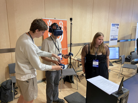 Andželika un Eduards demonstrē virtuālās realizātes lietojumu profesoram no Latvijas Universitātes